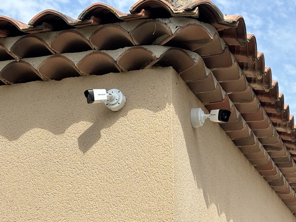 Deux caméras de surveillance fixées à l'angle d'une maison sous les tuiles